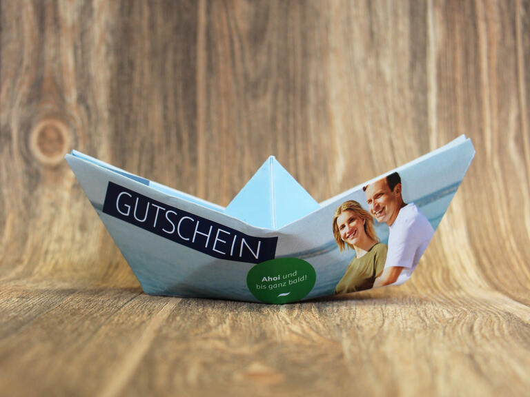 Mit einem gefalteten Segelboot als Geschenkgutschein ein Bodensee Erlebnis verschenken.