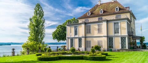 Blick auf das Schloss Arenenberg vor blauem Himmel.