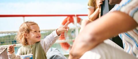 Ein Kind beim Eis essen mit dem Eltern im Hintergrund auf dem Schiff.