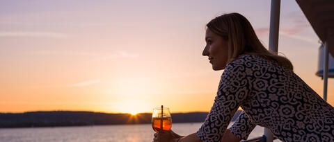Frau an der Reling bei Sonnenuntergang