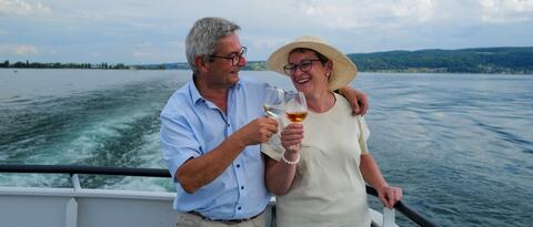 Ein Ehepaar stößt an Bord eines Schiffs mit Ihren Gläsern an