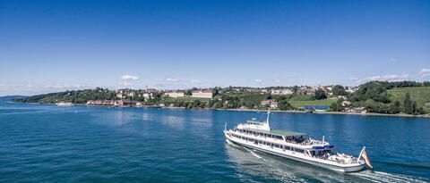 Schiff der Bodensee-Schifffahrt fährt auf dem Bodensee mit blauem Himmel.