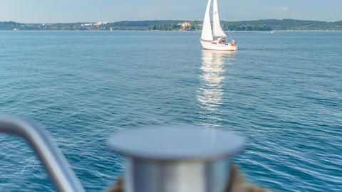 Blick vom Schiff auf den Bodensee mit einem Segelboot.