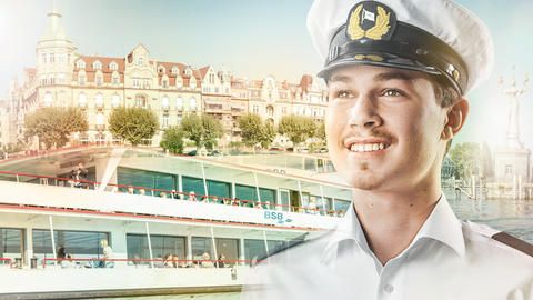 Junger Kapitän mit einem Schiff der Bodensee Schifffahrt im Hintergrund.