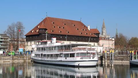 Ein Schiff der Bodensee Schifffahrt im Konstanzer Hafen, mit dem Konzil im Hintergrund  