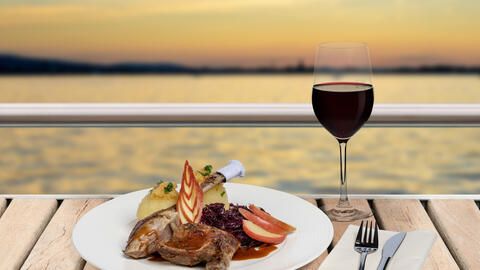 Teller mit leckeren Gans essen auf dem Schiff, dazu ein Rotwein mit Blick auf den Bodensee.