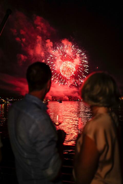 Ein Mann und eine Frau blicken auf das Feuerwerk über dem See