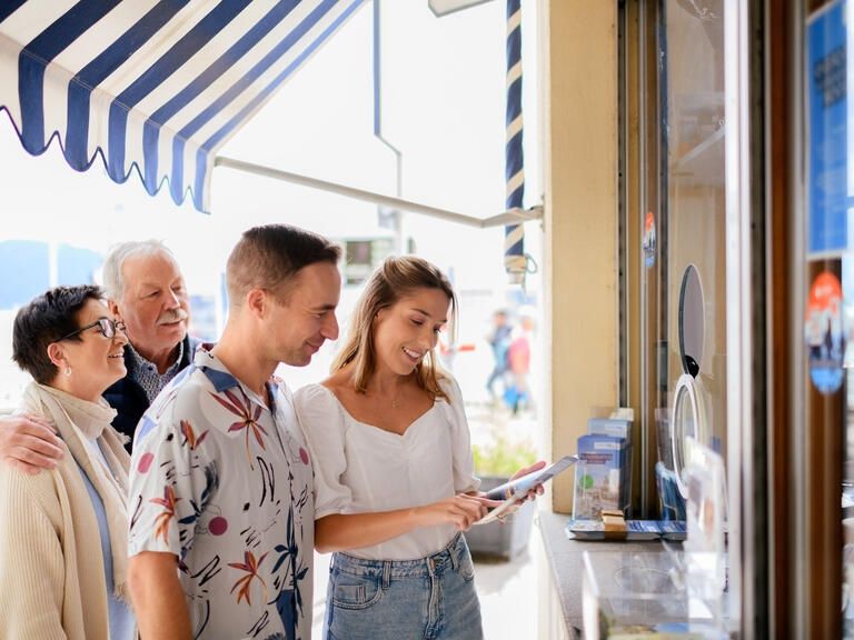 Familie mit vier Personen steht an einer Ticketverkaufstelle und planen eine Schifffahrt.