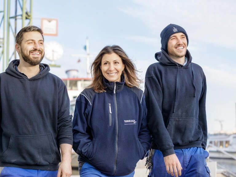 Mitarbeitende der Werft der Bodensee-Schiffsbetriebe lachen auf dem Werftgelände in Konstanz.