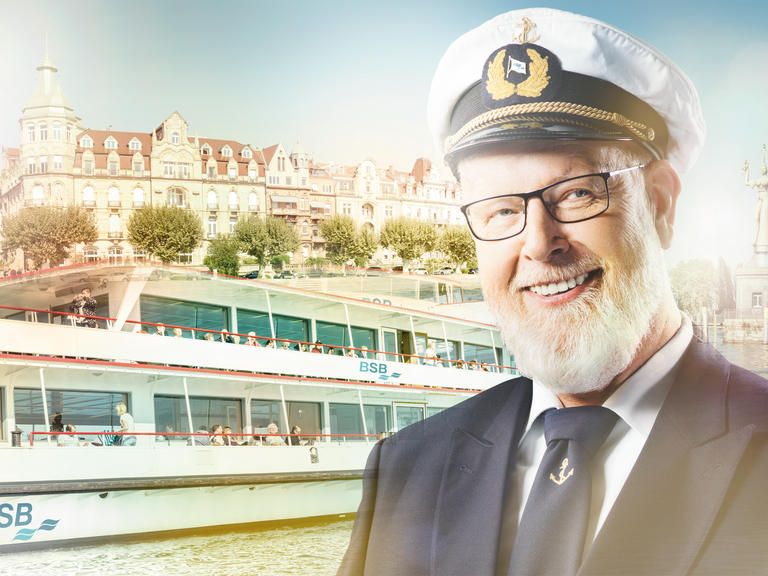 Lächelnder Kapitän mit Schiff er Bodensee Schifffahrt im Hintergrund in einem leichten Goldschimmer.