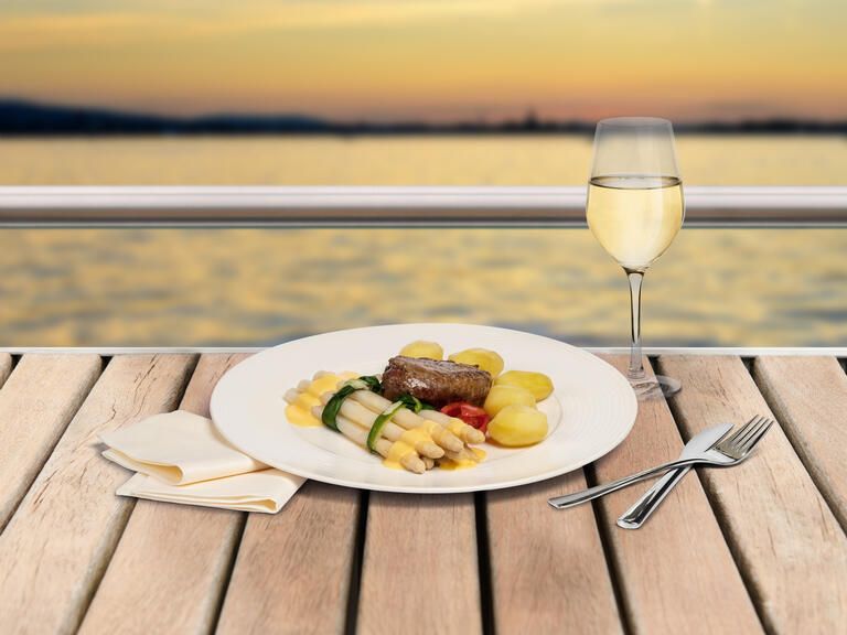 Ein Spargelteller mit Weißwein und den Blick auf den See bei einer Spargelfahrt genießen. 