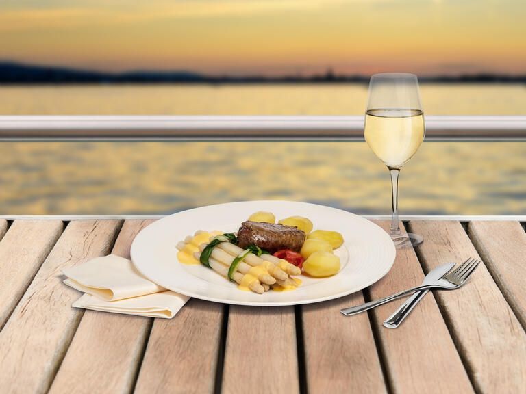 Ein Spargelteller mit Weißwein und den Blick auf den See bei einer Spargelfahrt genießen.