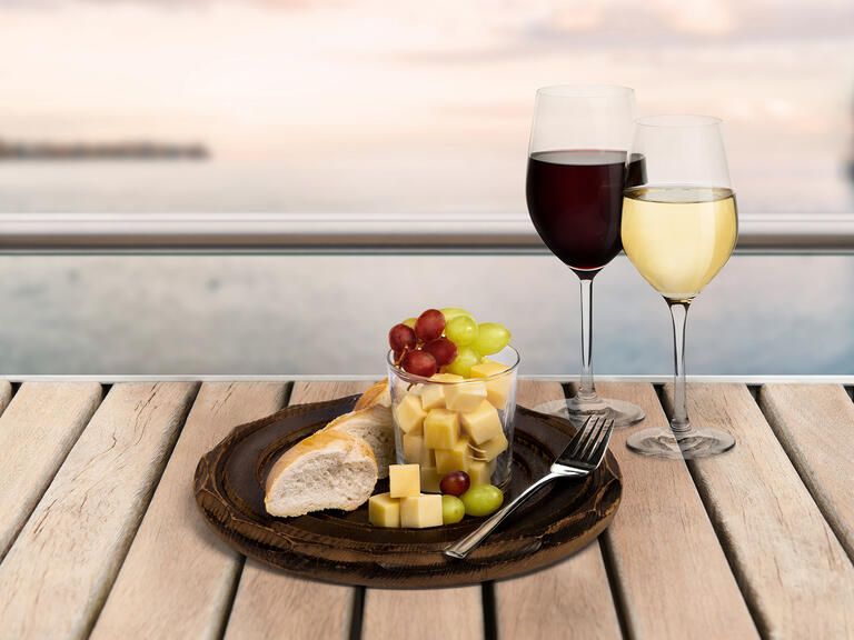 Schifffahrt mit Essen, Käsewürfel und Trauben dazu Rot- und Weißwein, im Hintergrund der Bodensee.