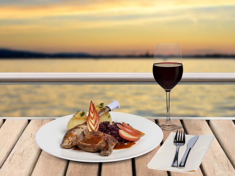 Teller mit leckeren Gans essen auf dem Schiff, dazu ein Rotwein mit Blick auf den Bodensee.