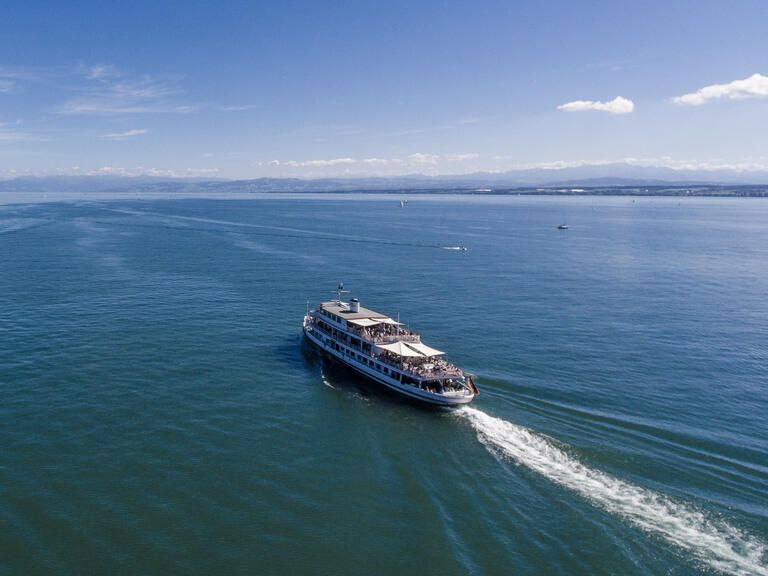 Schiff der Bodensee-Schifffahrt fährt auf dem Bodensee mit blauem Himmel.