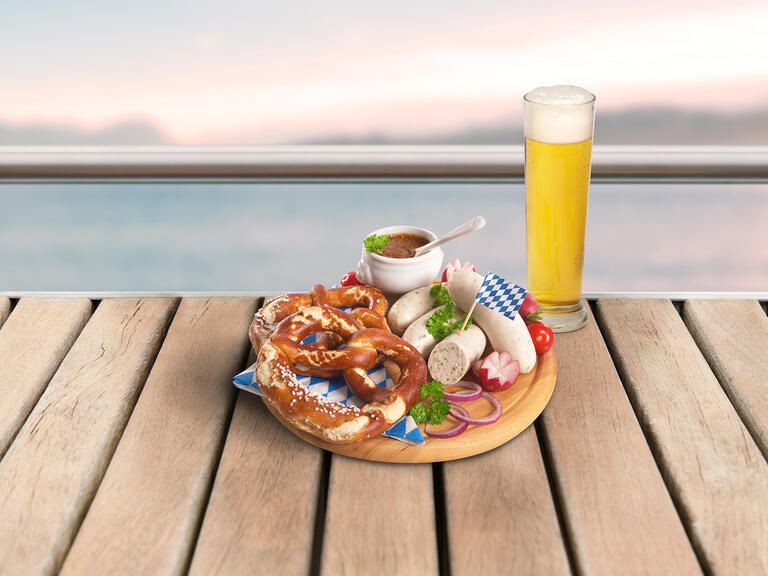 Ein Vesperbrett mit bayrischen Spezialitäten und ein Weißbier bei einer Schifffahrt mit Essen und Blick auf den Bodensee.