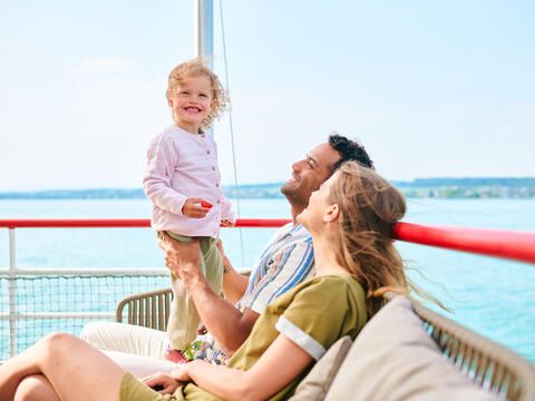 Ein Mann, eine Frau und deren kleine Tochter verbringen Familienzeit auf dem Schiff.