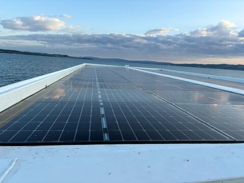  Solarpanels glänzen im Sonnenlicht, weiter Blick über den See