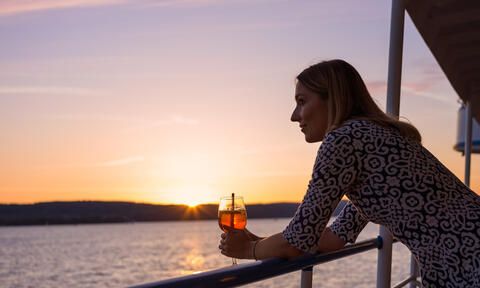 Frau an der Reling bei Sonnenuntergang