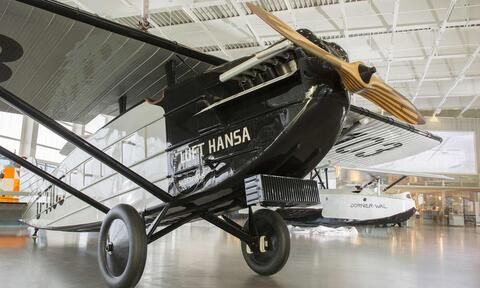 Blick auf ein altes schwarzes Flugzeug in einer großen Halle im Dornier Museum Friedrichshafen